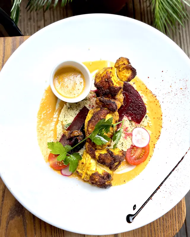 Brochette dorée sur semoule, betterave, radis et sauce safranée, vue de dessus